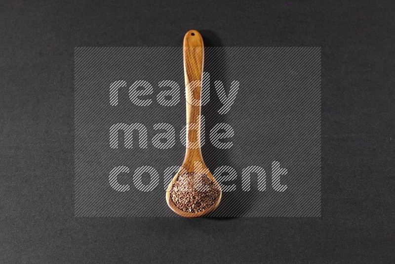 A wooden ladle full of flax on a black flooring in different angles