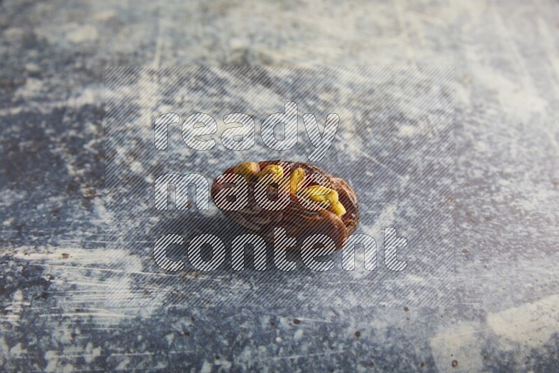 pistachios stuffed madjoul date on a rustic blue background