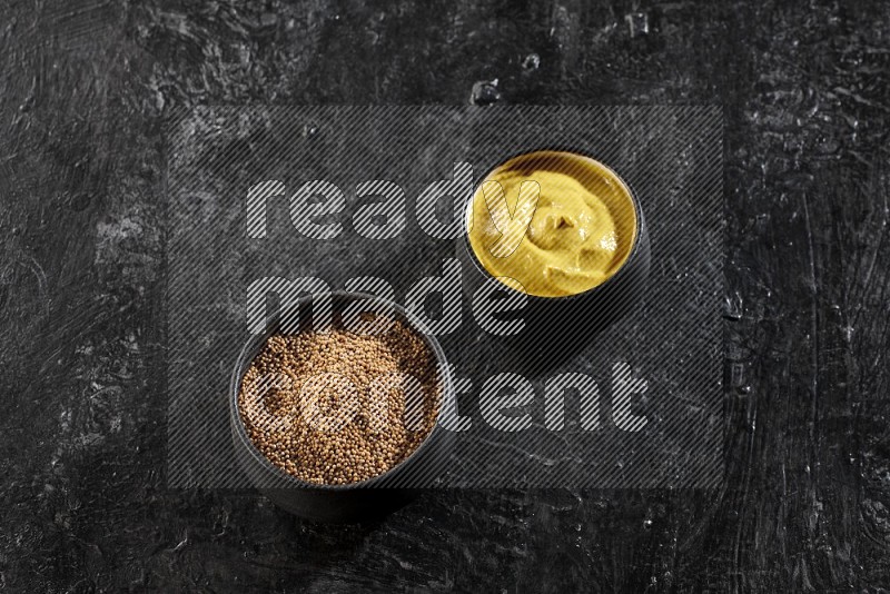 2 black pottery bowls full of mustard seeds and mustard paste on black flooring in different angles