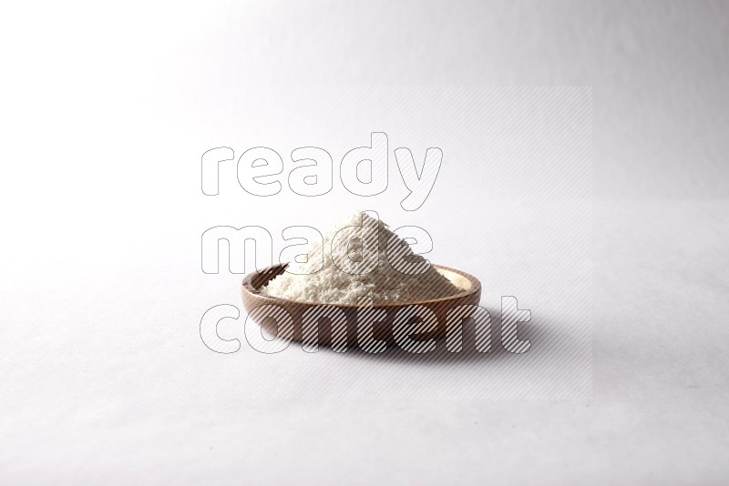 Desiccated coconuts in a wooden bowl on white background