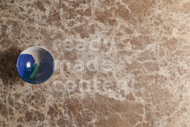 A multicolored pottery bowl on beige marble background