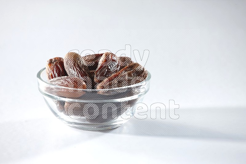 A glass bowl full of dried dates on a white background in different angles