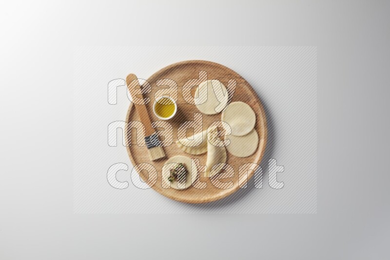 two closed sambosas and one open sambosa filled with meat while oil with oil brush aside in a wooden dish on a white background