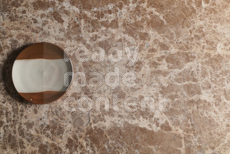 A decorative pottery plate on beige marble background