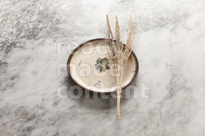 Wheat stalks on decorative pottery plate on grey marble background