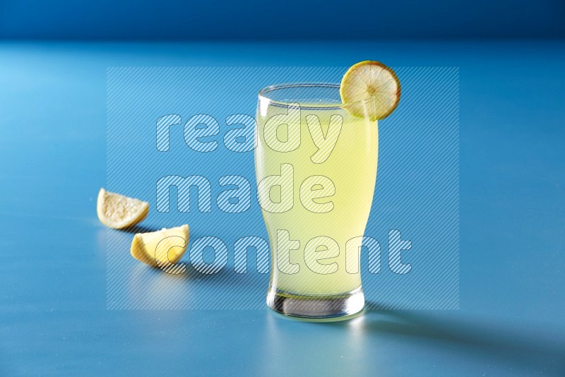 glass of lemon juice with lemon slice  on blue background