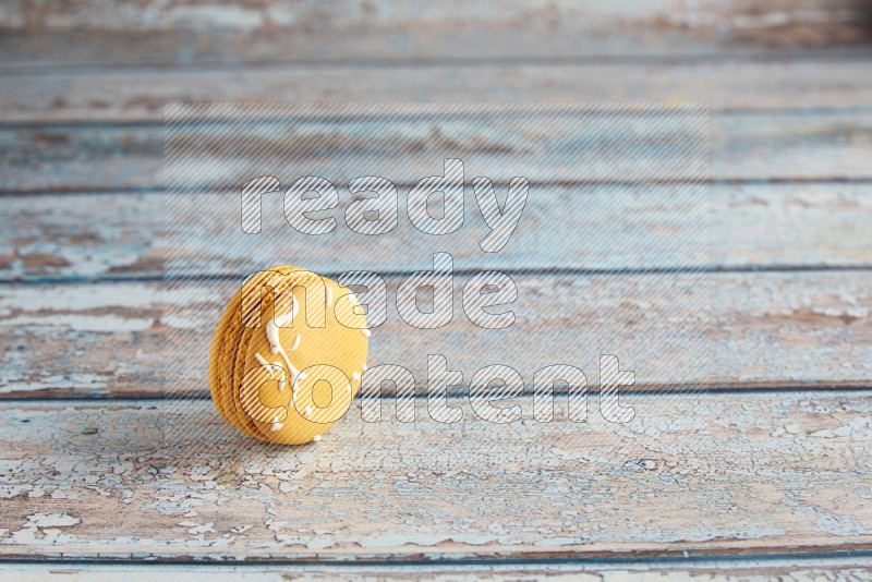 45º Shot of Yellow Piña Colada macaron on light blue wooden background