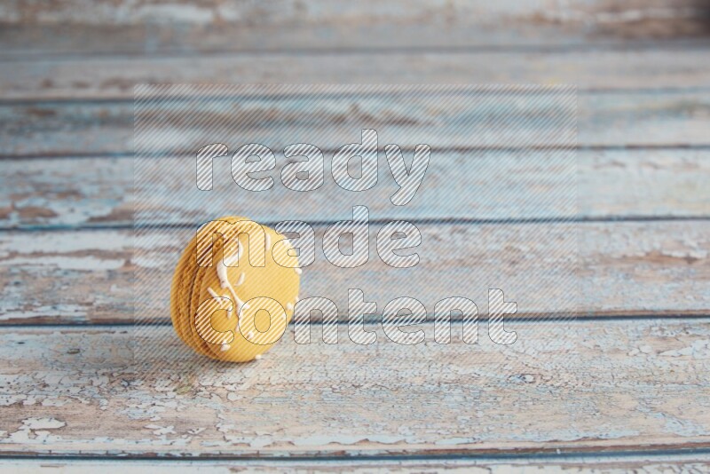 45º Shot of Yellow Piña Colada macaron on light blue wooden background