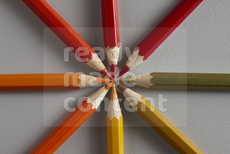 مجموعة من الأقلام الخشبية الملونة بتدرجات اللون البرتقالي والأحمر على خلفية رمادية