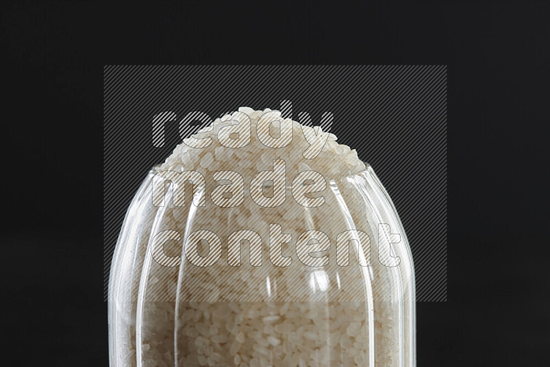 White rice in a glass jar on black background