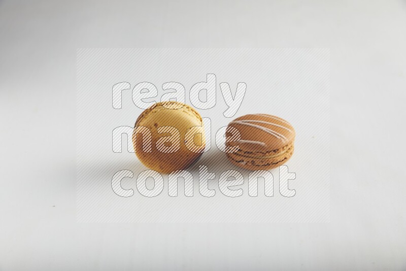45º Shot of of two assorted Brown Irish Cream, and Yellow Crème Brulée macarons on white background