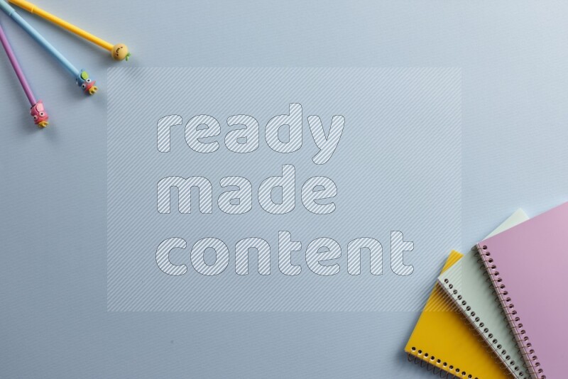 Multicolored notebooks with different school supplies on blue background