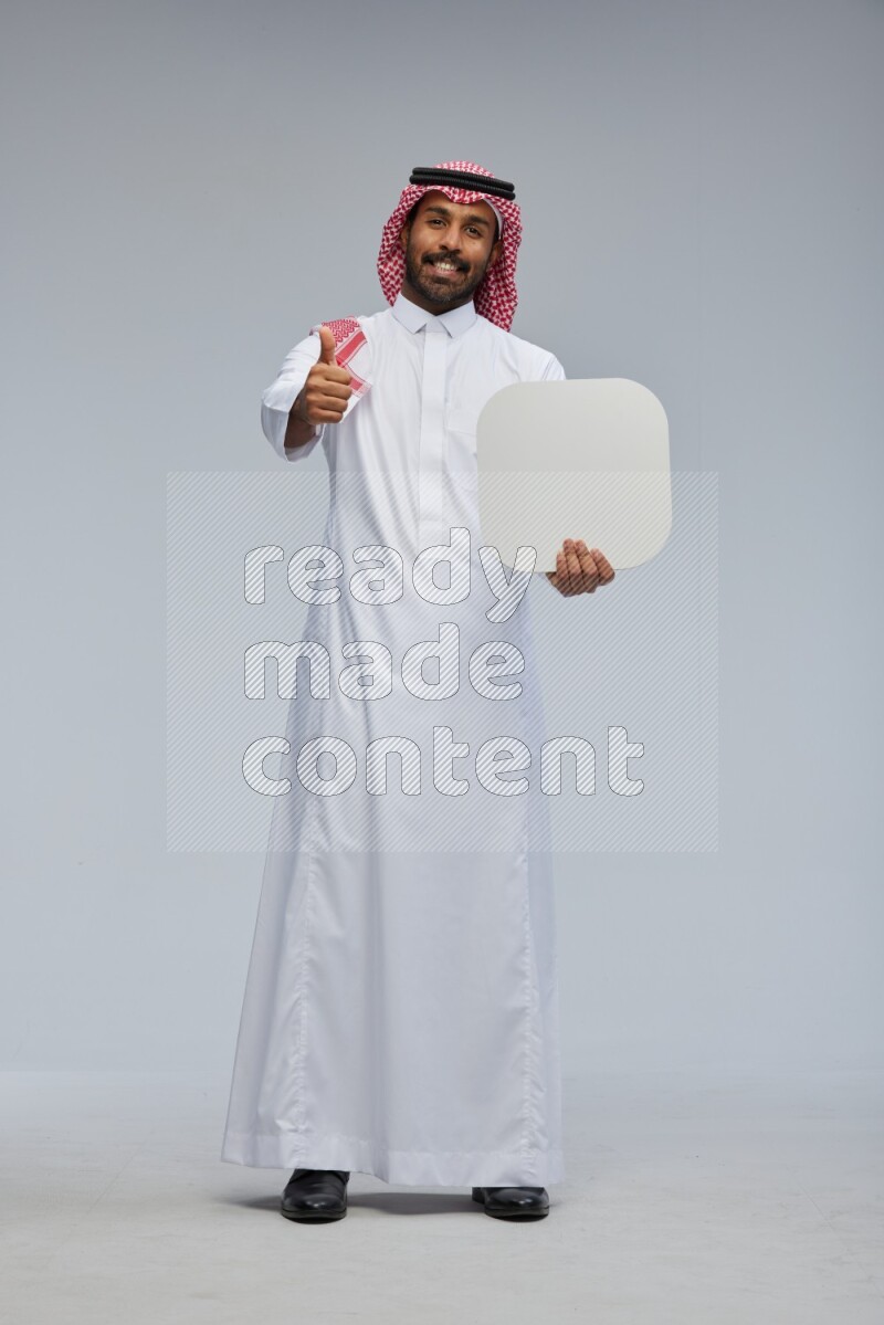 Saudi man Wearing Thob and shomag standing holding social media sign on Gray background