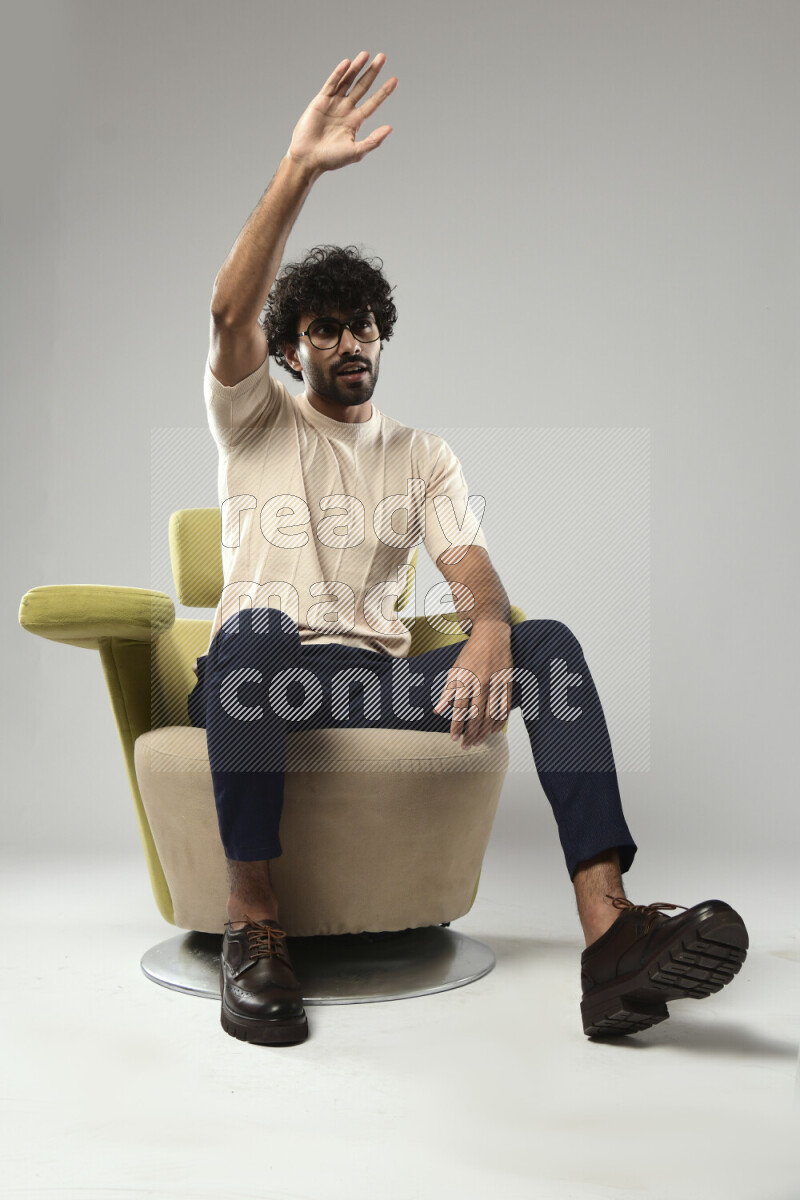 A man wearing casual sitting on a chair making a hand gesture on white background