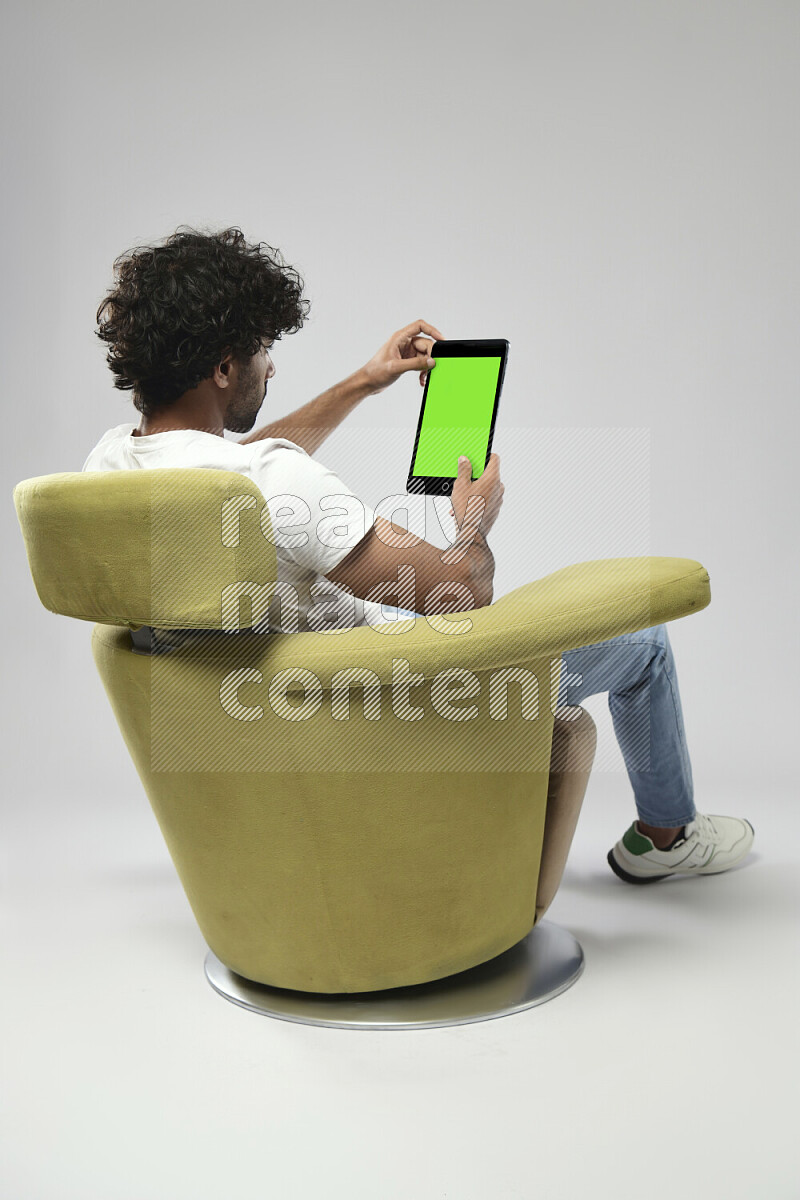 A man wearing casual sitting on a chair showing a tablet screen on white background