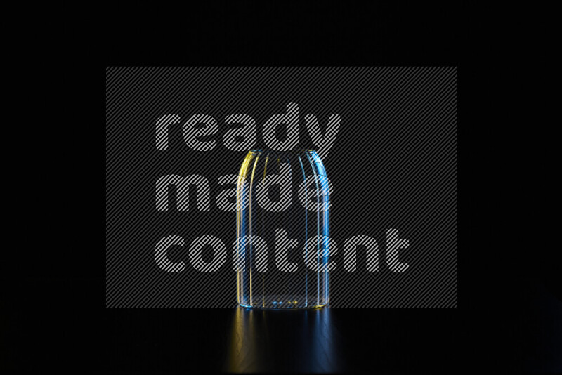 Glassware with rim light in blue and yellow against black background