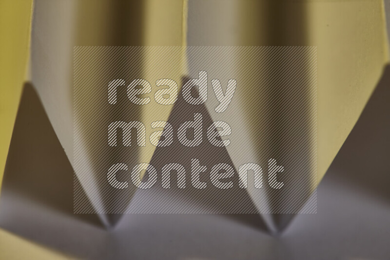 A close-up abstract image showing sharp geometric paper folds in warm gradients