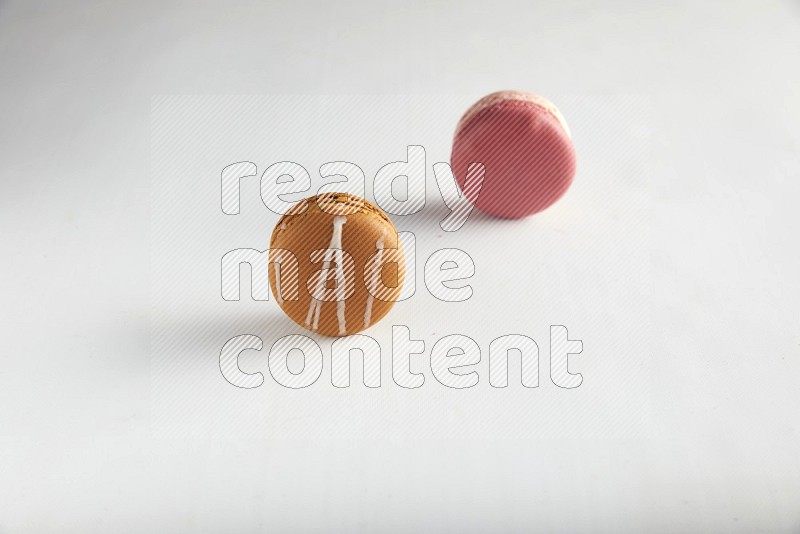 45º Shot of of two assorted Brown Irish Cream, and Pink Litchi Raspberry macarons on white background