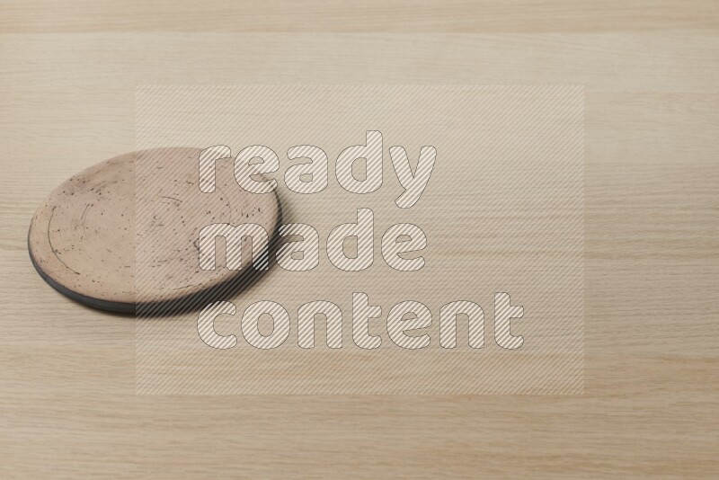 A pottery coaster on light wooden background