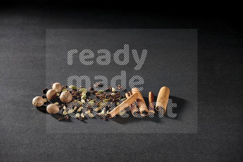 Cardamom, cloves, nutmeg and cinnamon sticks on black flooring