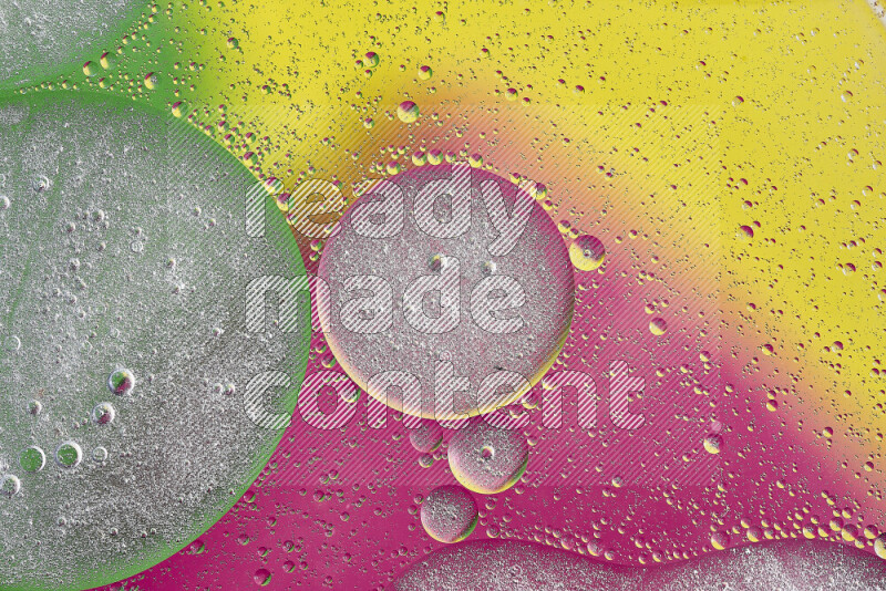 Close-ups of abstract oil bubbles on water surface in shades of yellow, green and pink