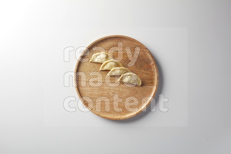 Four Sambosas on a wooden round plate on a white background