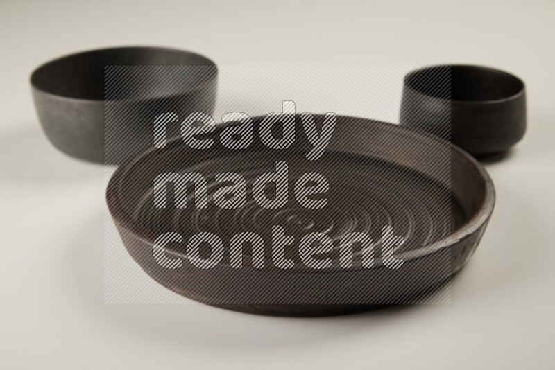 black pottery plate and black bowls on white background