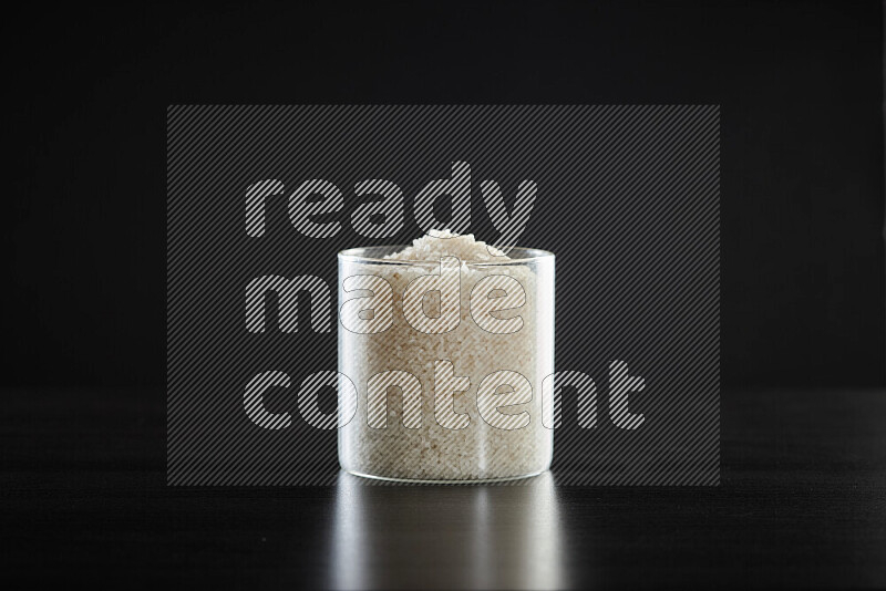 White rice in a glass jar on black background