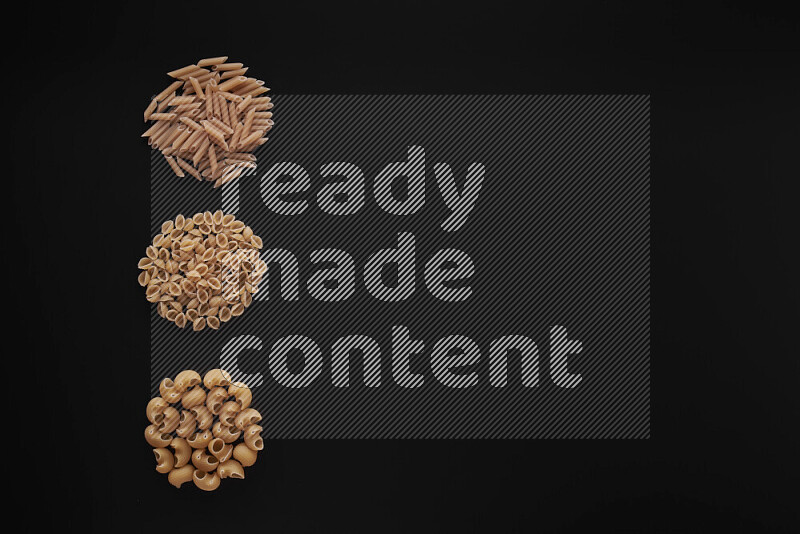 Different pasta types in 3 bunches on black background