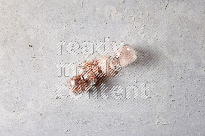 2 glass jars one is filled with fine himalayan salt and the other with coarse himalayan salt on white background