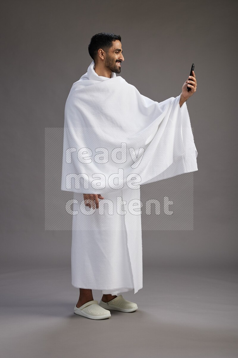 A man wearing Ehram Standing taking selfie on gray background