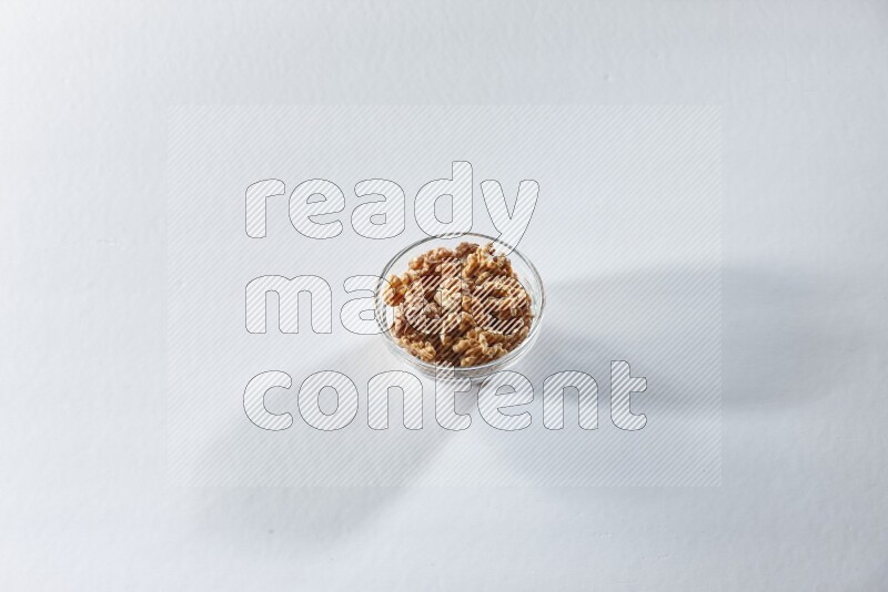 A glass bowl full of peeled walnuts on a white background in different angles