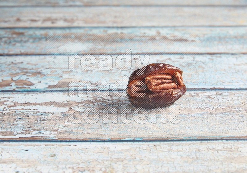 pecan stuffed madjoul date on a light blue wooden background