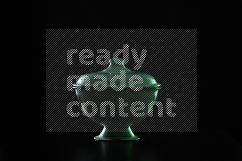 A vintage metal pot with colored rim light against black background