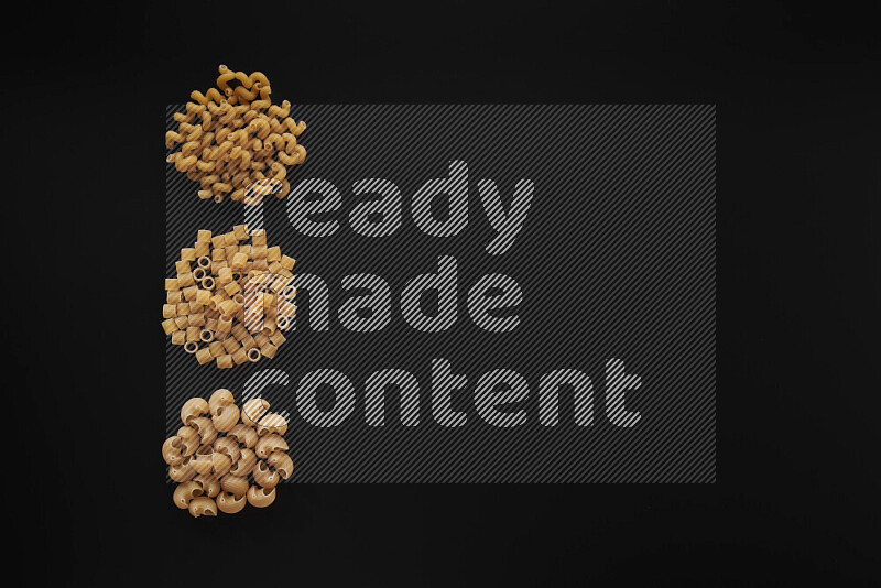 Different pasta types in 3 bunches on black background