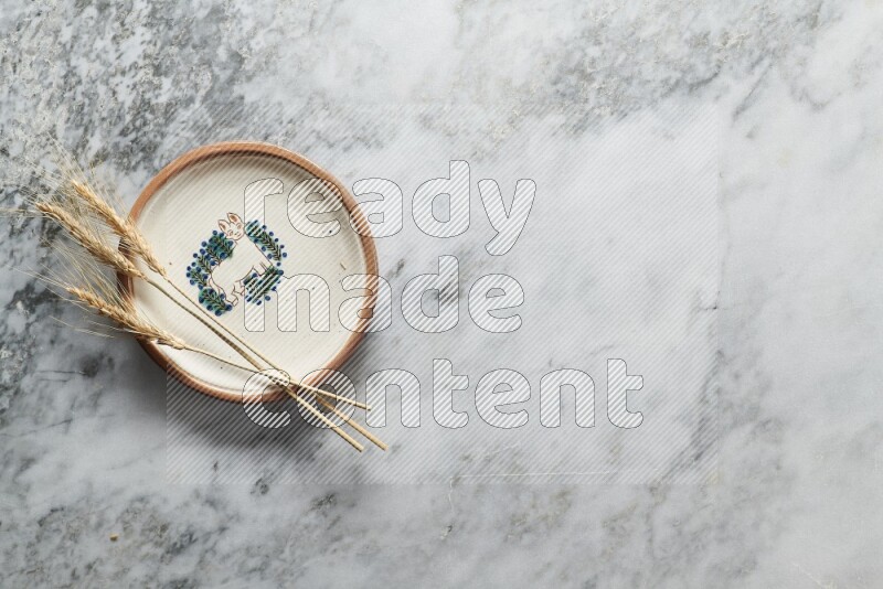 Wheat stalks on decorative pottery plate on grey marble background