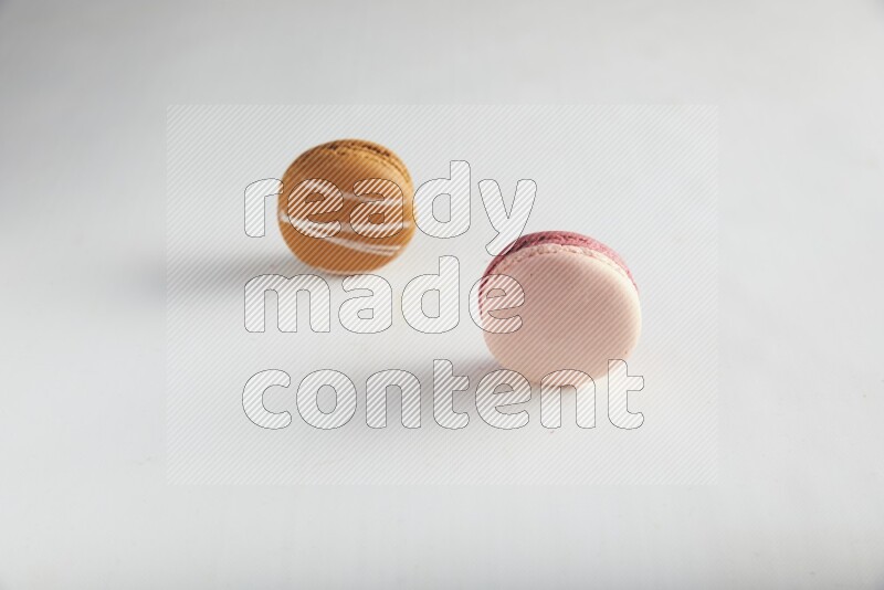 45º Shot of of two assorted Brown Irish Cream, and Pink Litchi Raspberry macarons on white background