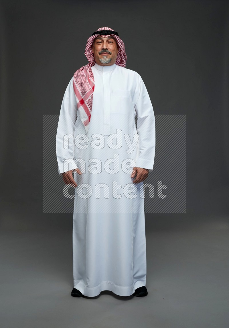 Saudi man with shomag Standing Interacting with the camera on gray background