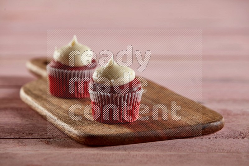 Red velvet mini cupcake topped with cream on a wooden board