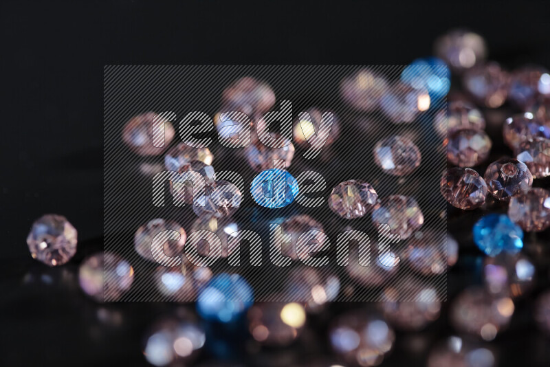 Rose and blue transparent crystal beads scattered on a black background