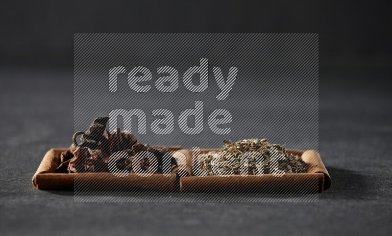 2 squares of cinnamon sticks full of cumin and star anise on black flooring