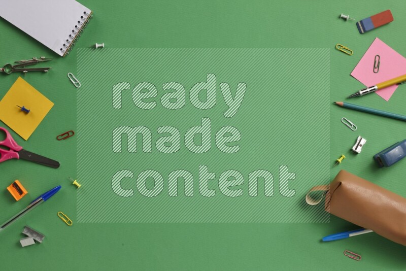 Different school supplies on green background