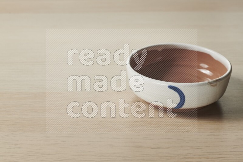 A multicolored pottery bowl on light wooden background