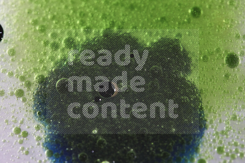 لقطات مقربة لقطرات ألوان مائية خضراء وزرقاء على سطح الزيت على خلفية بيضاء