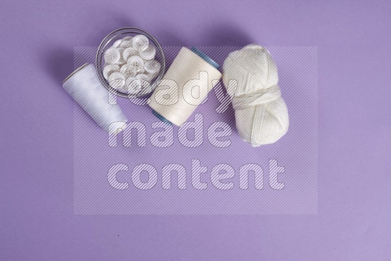 White sewing supplies on purple background