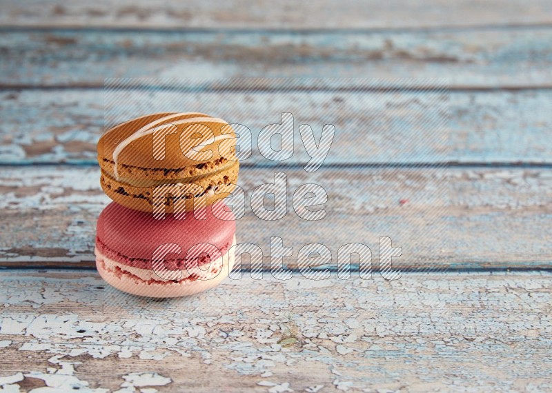 45º Shot of of two assorted Brown Irish Cream, and Pink Litchi Raspberry macarons on light blue background