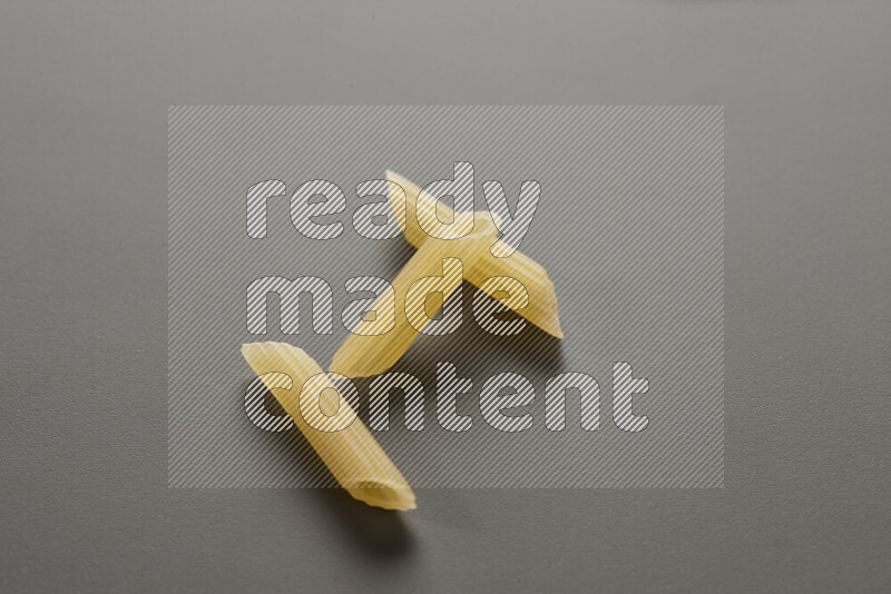 Mini penne pasta on grey background