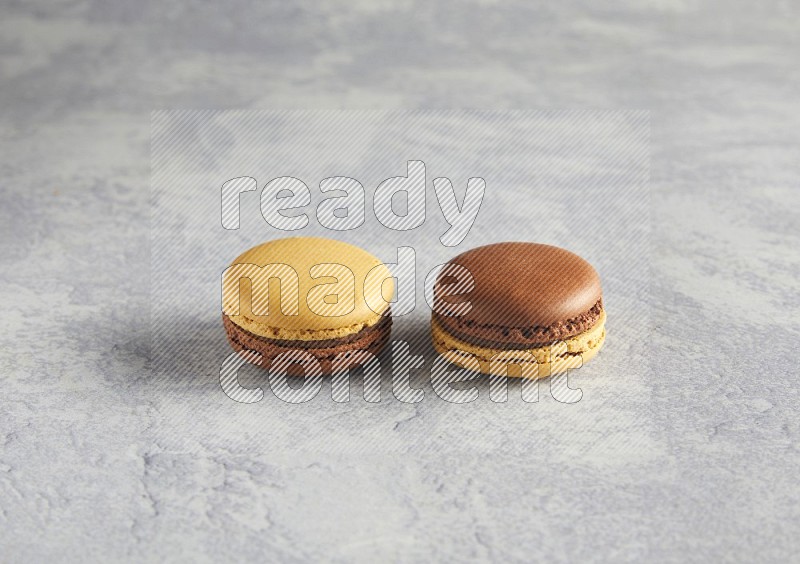 45º Shot of two Yellow and Brown Chai Latte macarons r on white  marble background