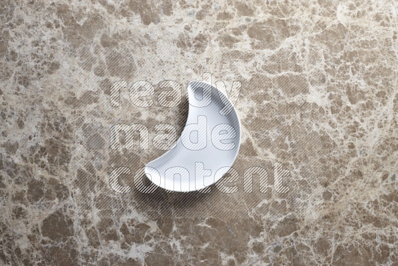 A pottery crescent plate on beige marble background