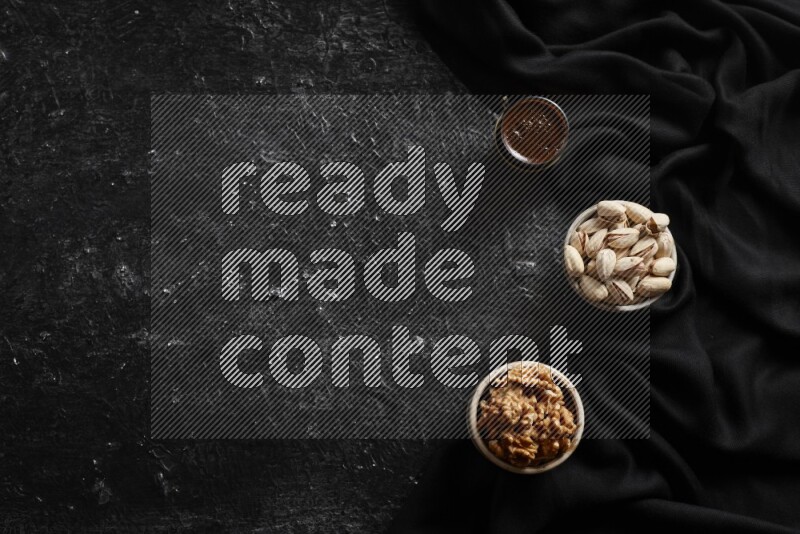 مكسرات في أطباق فخارية مع القهوة علي خلفية سوداء خشبية